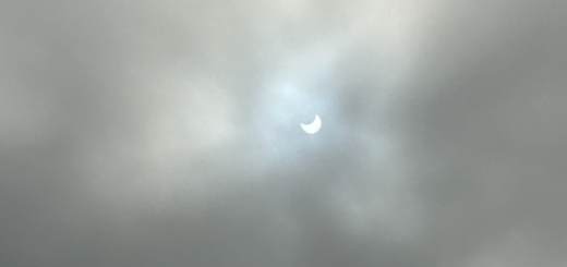 Partially eclipsed Sun peeking through clouds