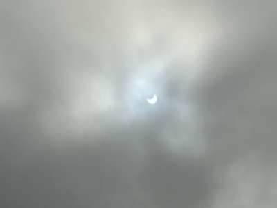 Partially eclipsed Sun peeking through clouds